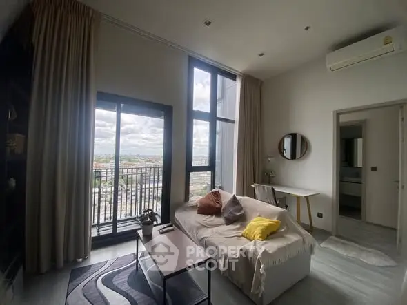 Modern living room with large windows and balcony view, featuring stylish decor and cozy seating area.