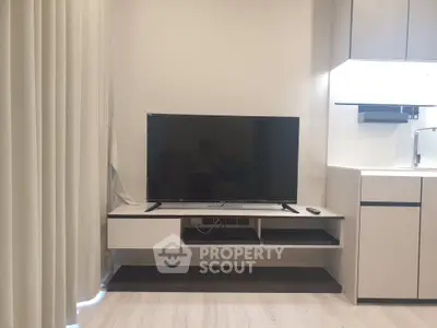 Modern living room with sleek TV setup and minimalist kitchen area.