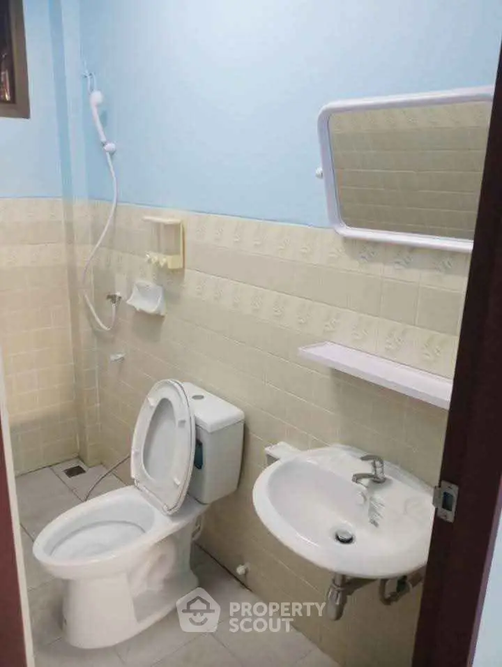 Compact bathroom with toilet, sink, and shower in a tiled setting.