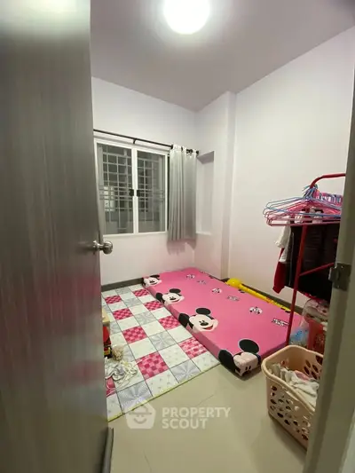 Cozy small bedroom with playful Mickey Mouse theme and ample natural light.