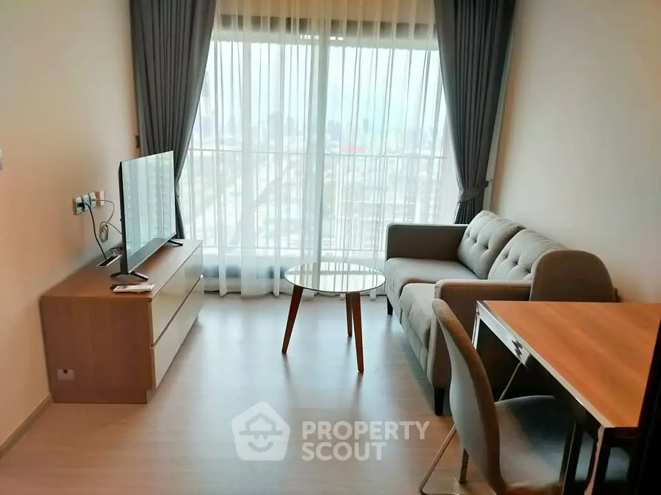Modern living room with large window and stylish furniture in a high-rise apartment.