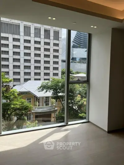 Spacious room with large windows offering a stunning city view, perfect for urban living.
