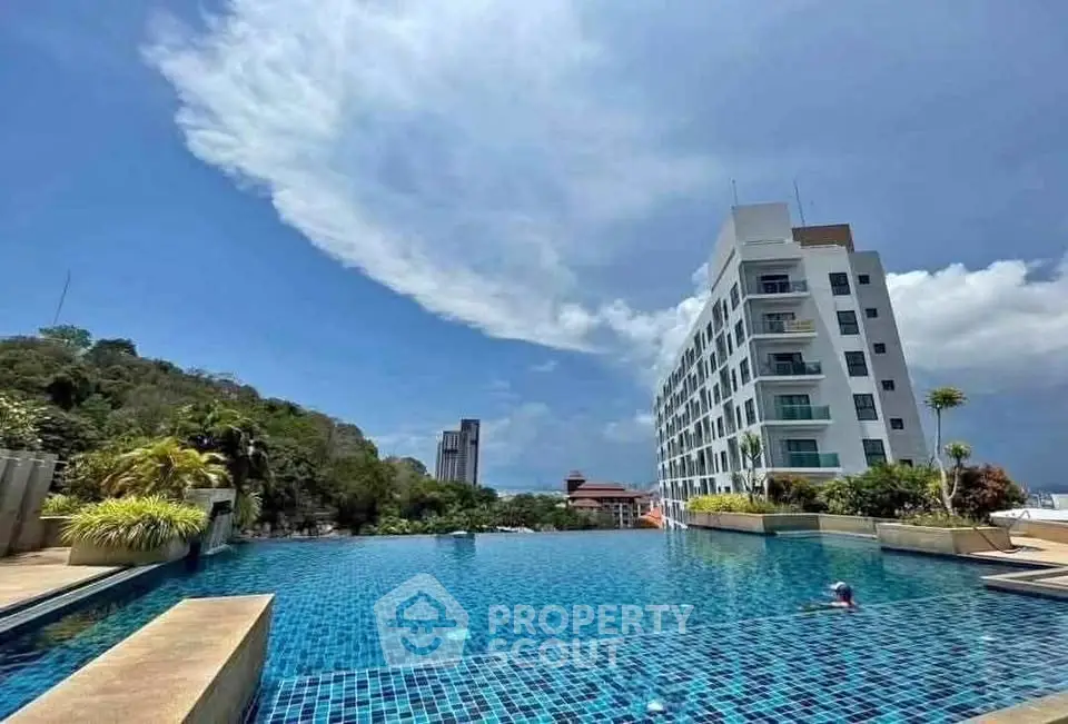 Stunning poolside view with modern building and lush greenery under a clear blue sky.