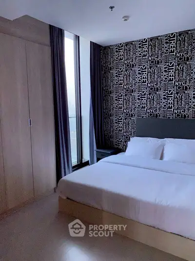 Modern bedroom with stylish wallpaper and large window for natural light.