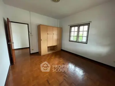 Spacious empty bedroom with wooden flooring and large wardrobe