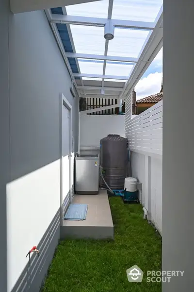 Modern outdoor laundry area with washing machine and water tank in a sleek backyard space.