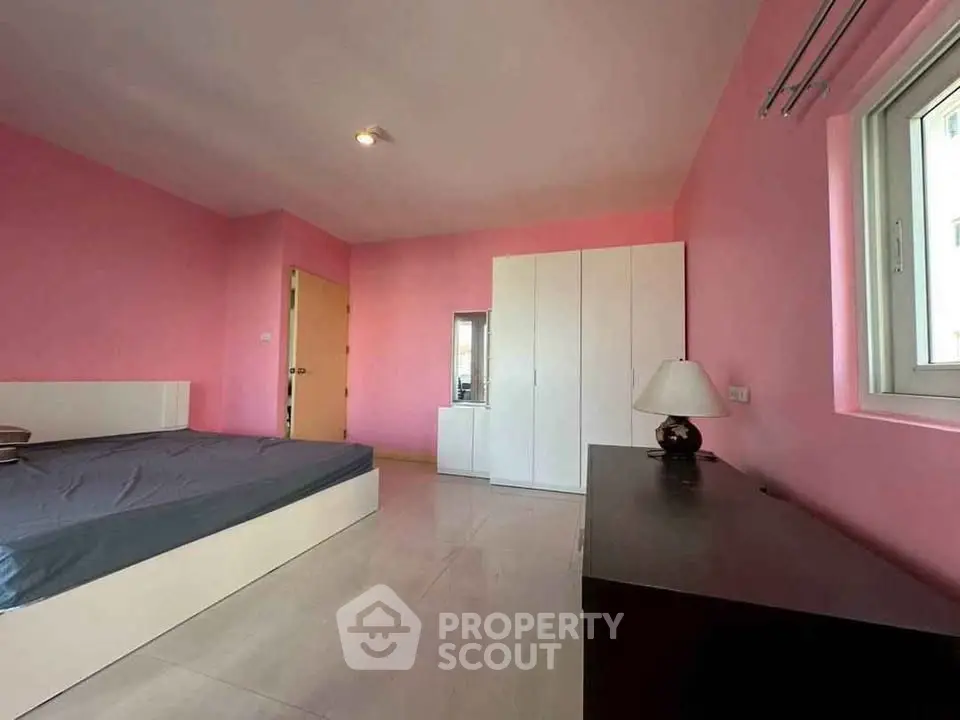 Spacious pink bedroom with modern furniture and natural light