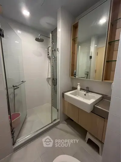 Modern bathroom with glass shower and sleek vanity in contemporary apartment.