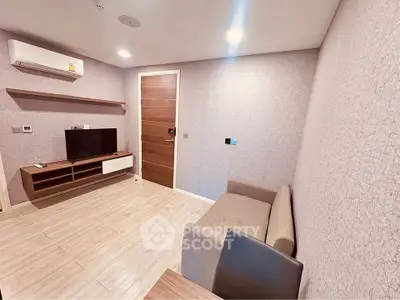 Modern living room with minimalist design, featuring a cozy sofa, wall-mounted TV, and air conditioning.