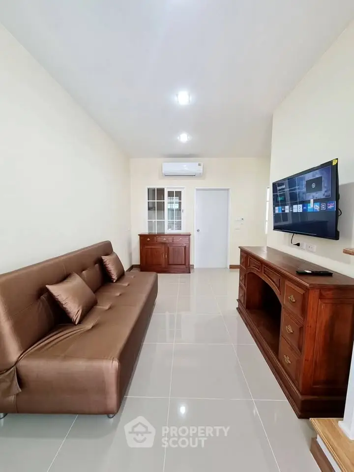 Modern living room with sleek brown sofa and wall-mounted TV in elegant apartment.