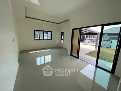 Spacious modern living room with large windows and sliding glass doors opening to a patio.