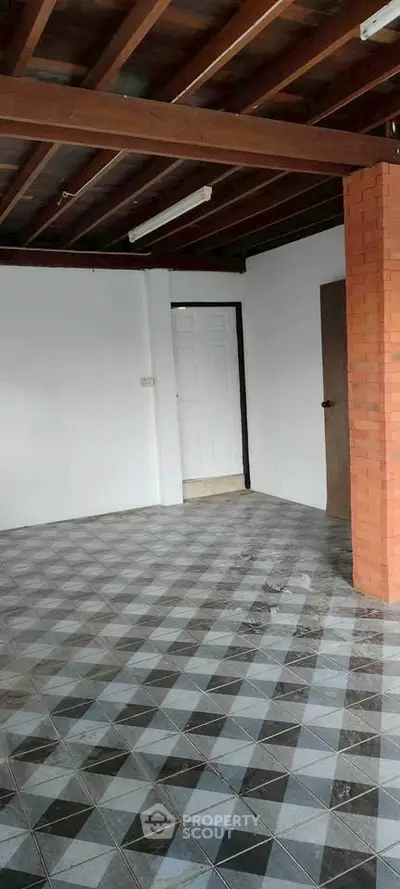 Spacious interior with unique tiled flooring and exposed wooden beams, perfect for customization.