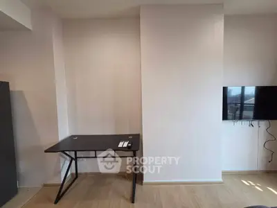 Modern minimalist study area with sleek desk and wall-mounted TV in a bright room.