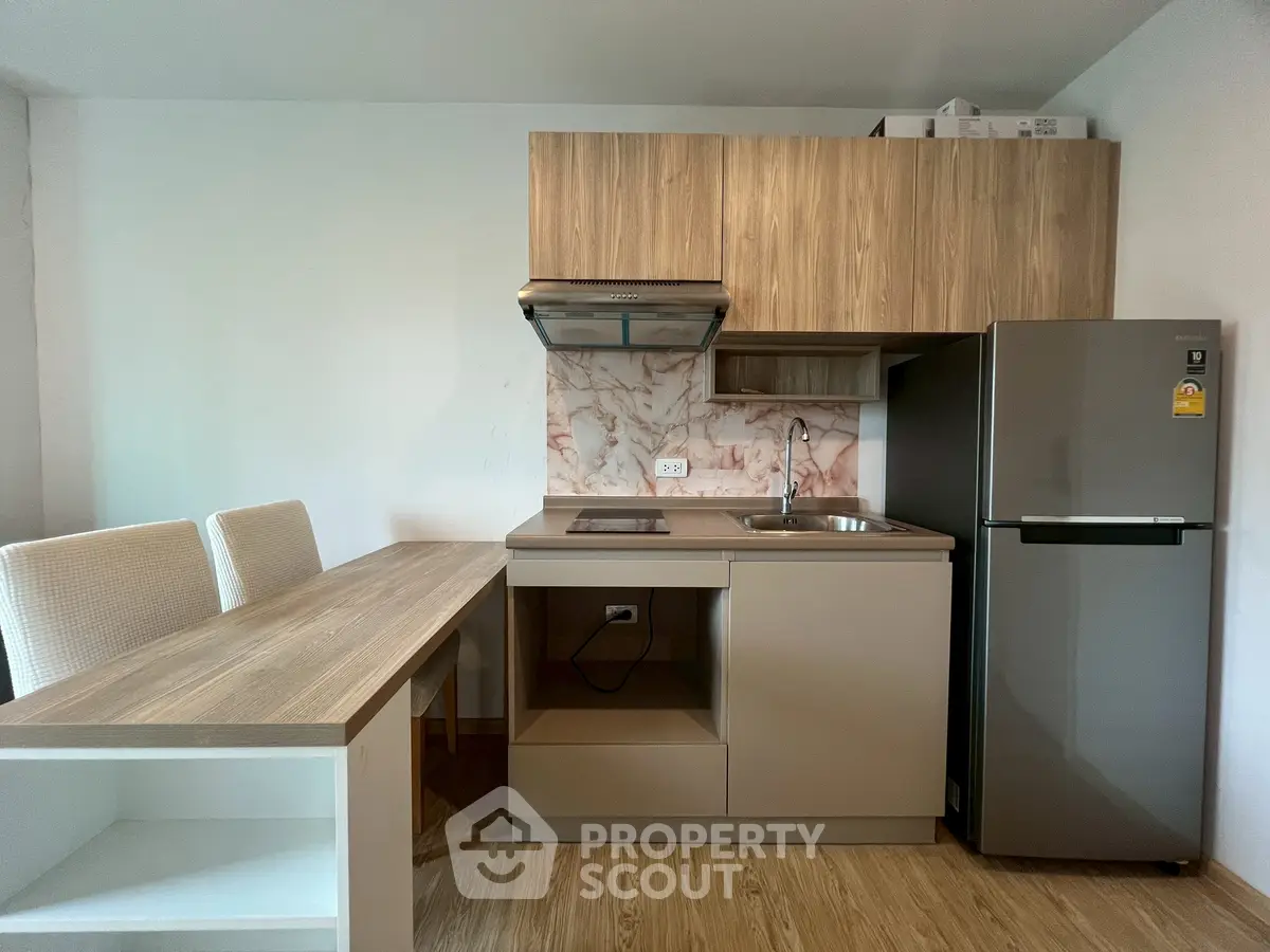 Modern kitchen with sleek cabinetry, compact dining area, and stainless steel appliances.