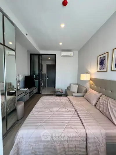 Modern bedroom with elegant decor, mirrored closet, and cozy seating area in a stylish apartment.