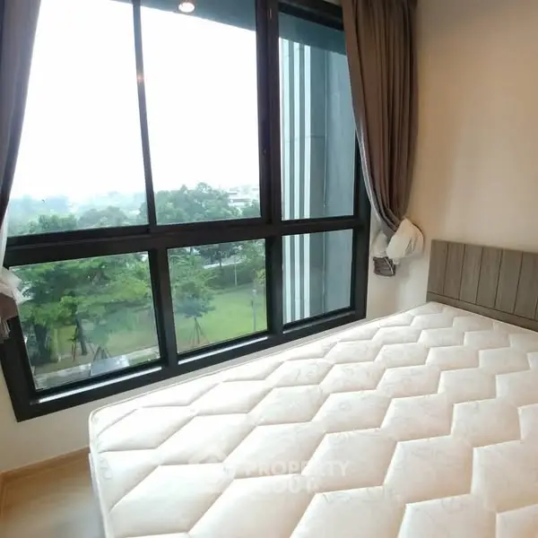 Bright bedroom with large windows offering a serene garden view, perfect for relaxation.