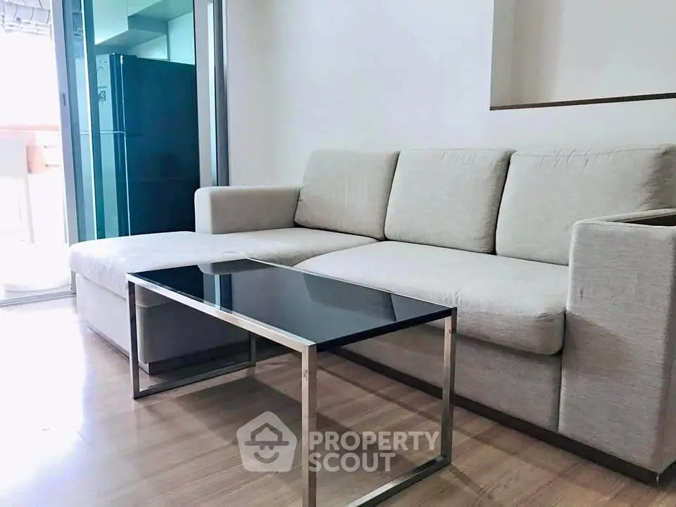 Modern living room with sleek sofa and glass coffee table in bright apartment.