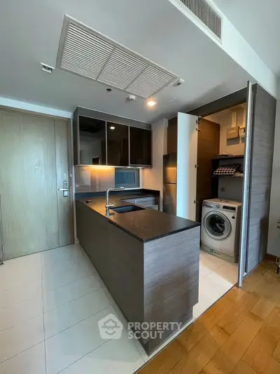 Modern kitchen with sleek design and built-in washing machine, featuring open layout and stylish cabinetry.