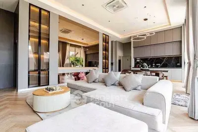 Luxurious open-plan living room with modern kitchen and elegant decor, featuring high ceilings and ample natural light.