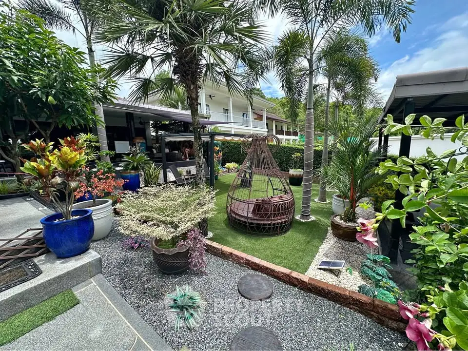 Tropical garden oasis with lush greenery and stylish outdoor seating in a modern residential setting.