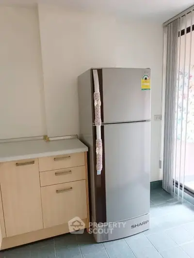 Modern kitchen with sleek refrigerator and light wood cabinetry, perfect for contemporary living.