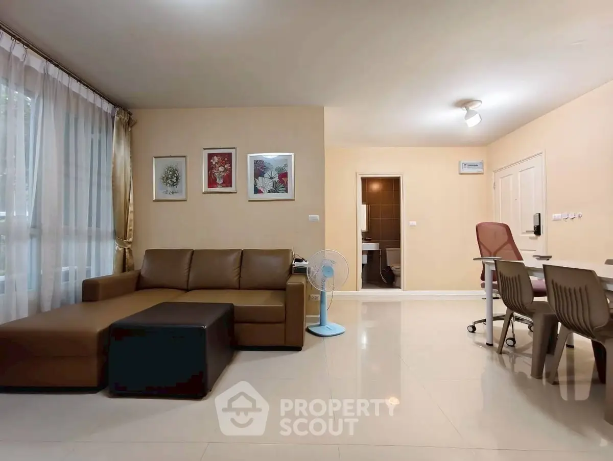 Spacious living room with modern decor and natural light, featuring a comfortable sofa and dining area.