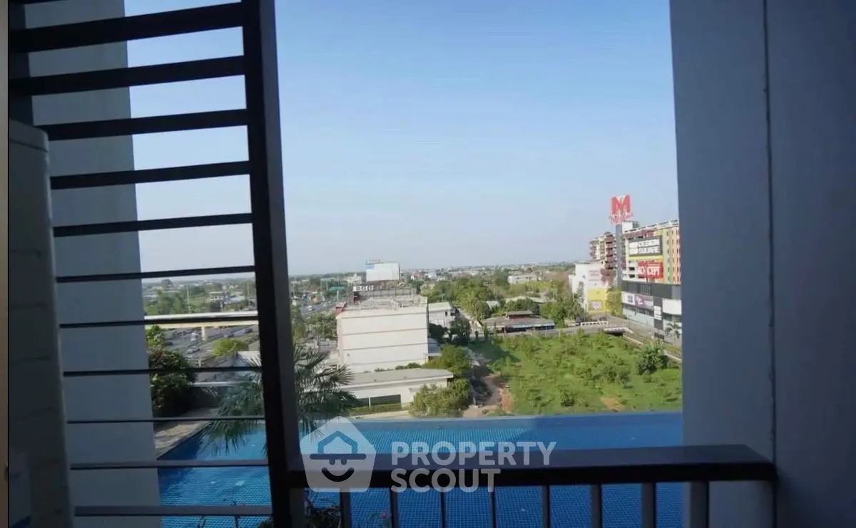 Stunning cityscape view from a high-rise balcony overlooking lush greenery and urban skyline.