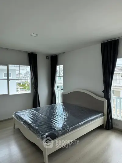 Spacious bedroom with large windows and modern decor in a bright, airy home.