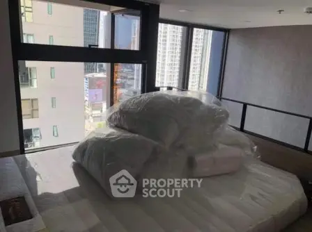 Modern bedroom with large windows offering city views, featuring a neatly made bed and contemporary design.