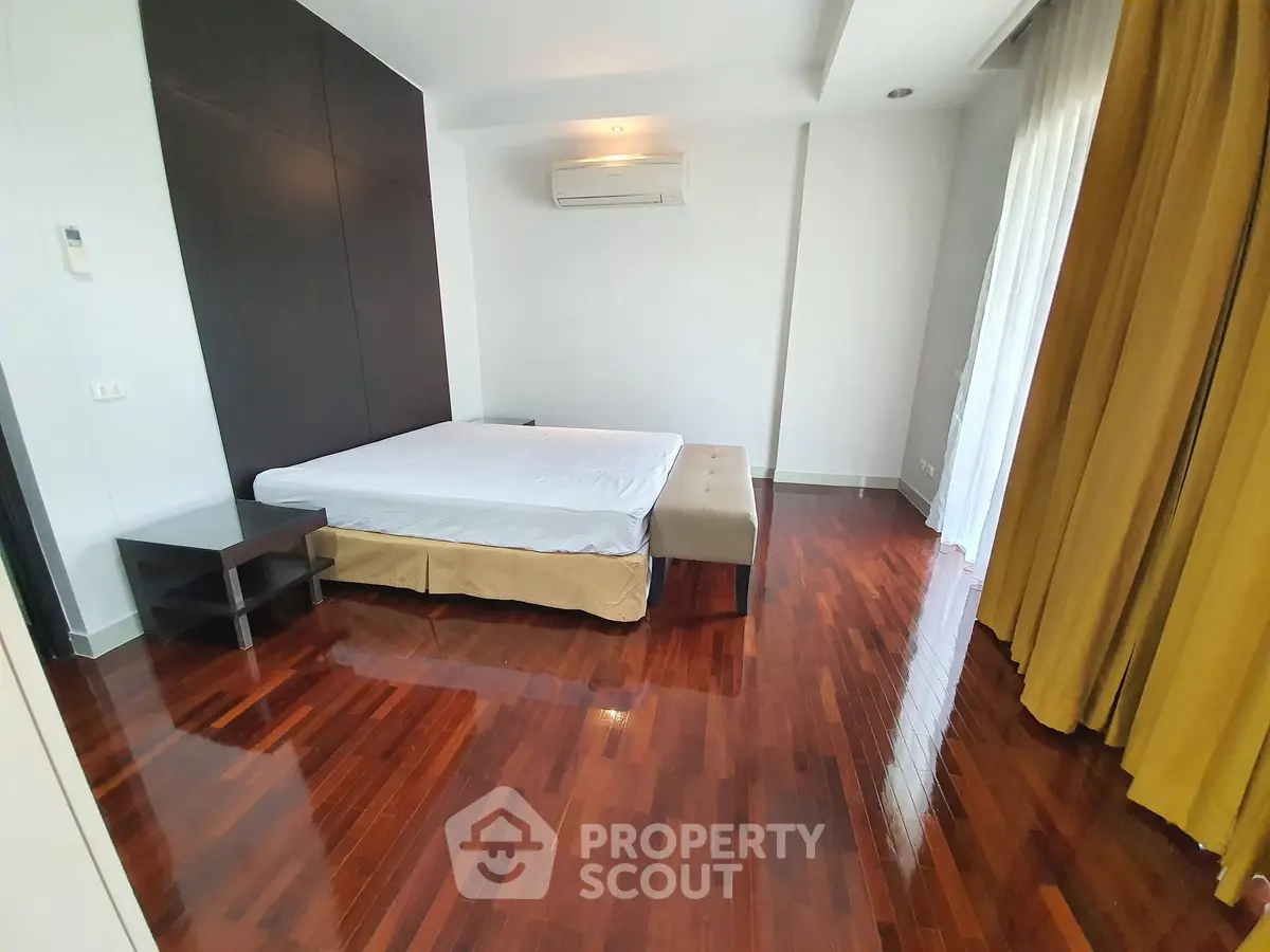 Spacious bedroom with polished wooden floors and modern decor