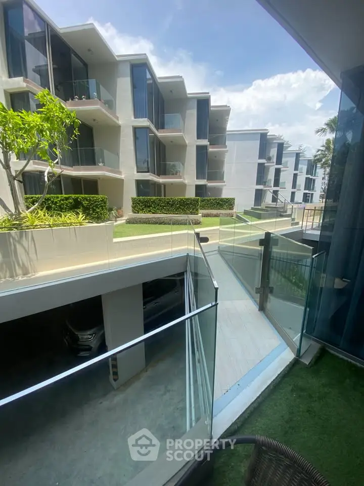 Modern apartment complex with glass balconies and lush landscaping
