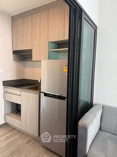 Modern compact kitchen with sleek cabinetry and stainless steel fridge in a cozy apartment.