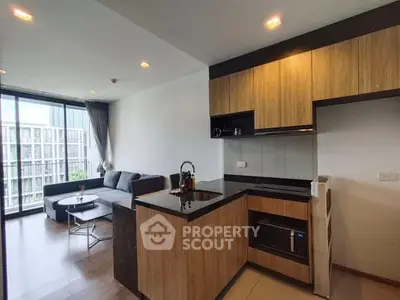 Modern open-layout kitchen with sleek wooden cabinets and cozy living area.
