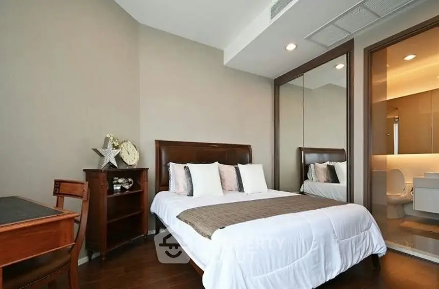 Elegant bedroom with wooden furniture and ensuite bathroom in modern apartment.