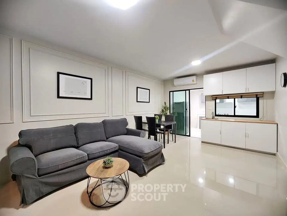 Modern living room with sleek gray sofa and open kitchen layout, perfect for contemporary living.
