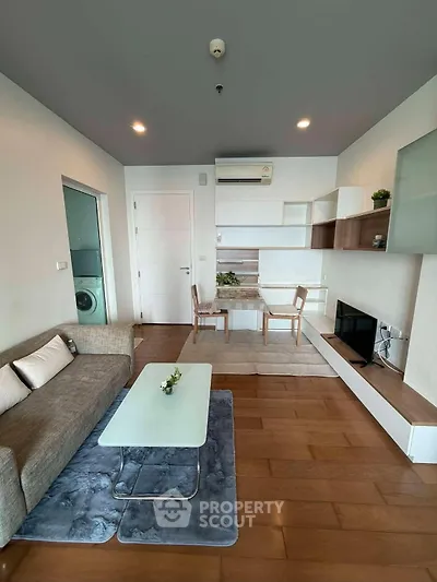 Modern living room with stylish furniture and wooden flooring, featuring a cozy sofa and a sleek coffee table.