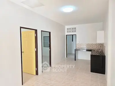 Spacious interior with tiled flooring and modern kitchen counter in a minimalist apartment.