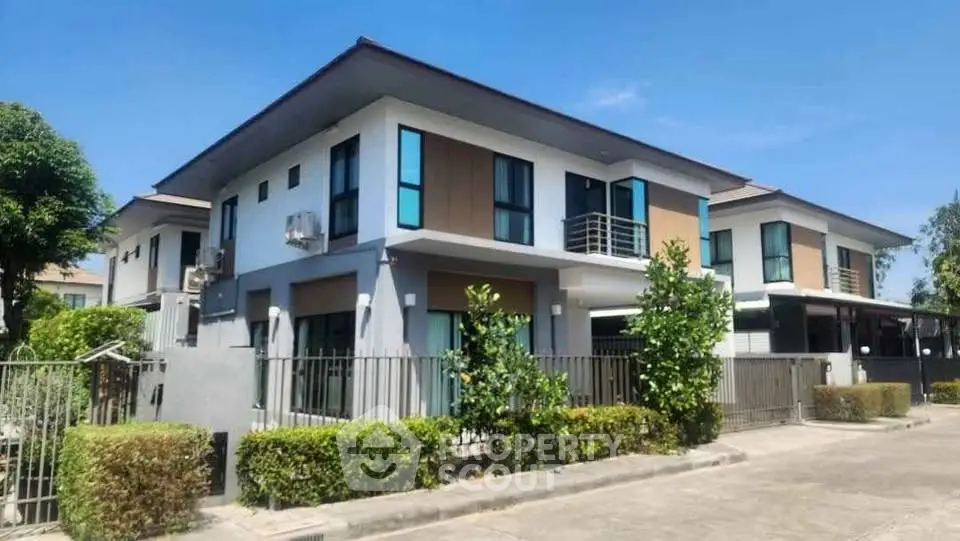 Modern two-story house with sleek design and lush greenery in a serene neighborhood.