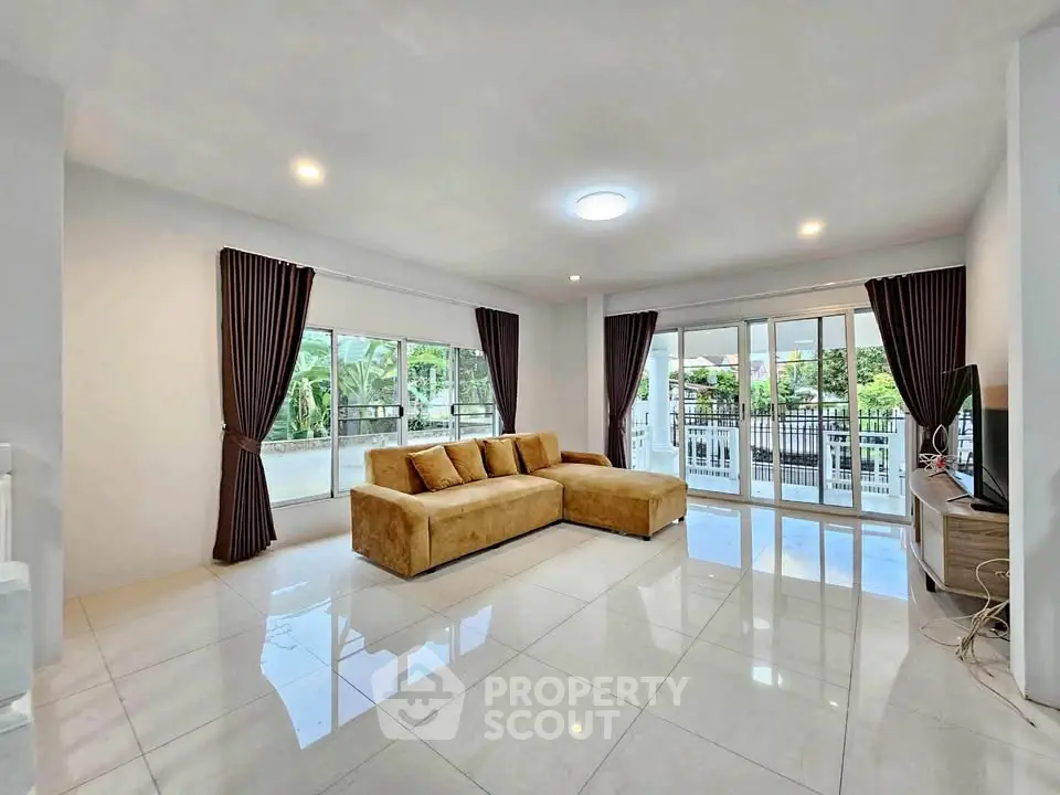 Spacious living room with modern sofa and large windows opening to a balcony view.