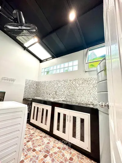 Modern kitchen with mosaic backsplash and ample storage in a well-lit space.