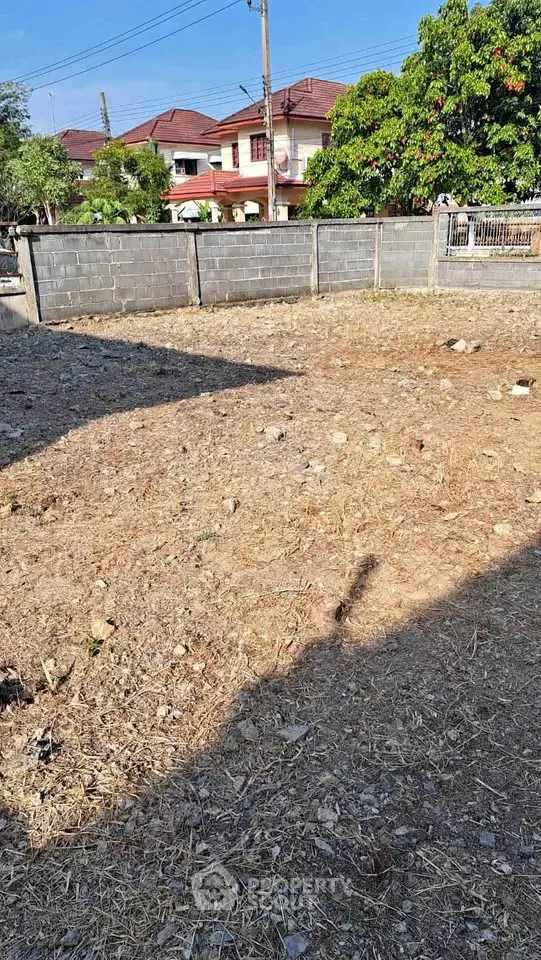 Vacant land plot in a residential area with potential for development, surrounded by houses and greenery.