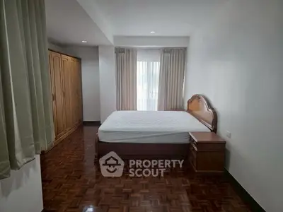 Spacious bedroom with wooden flooring and elegant furniture in a modern apartment.