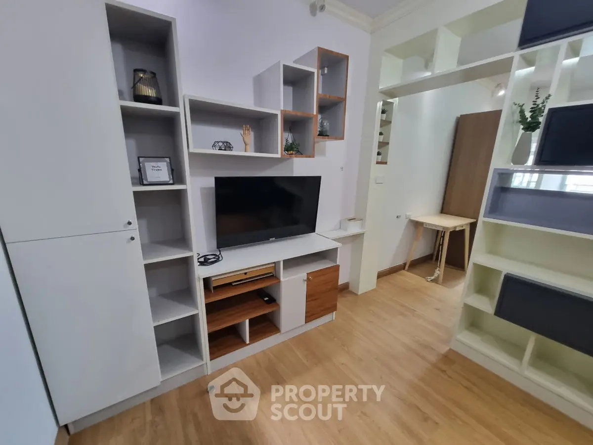 Modern living room with stylish shelving and TV unit, featuring wooden flooring and contemporary decor.