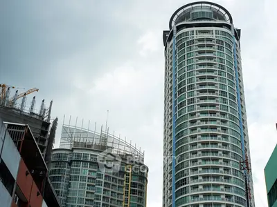Modern high-rise buildings with glass facades under a cloudy sky, showcasing urban architecture.