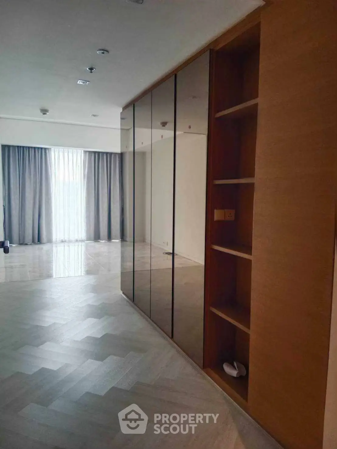 Spacious modern living room with elegant wood flooring and large mirrored closet.