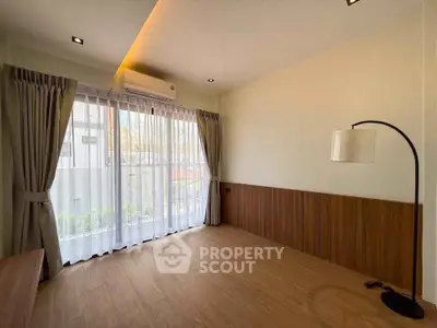 Spacious room with large window and modern floor lamp, perfect for versatile living space.