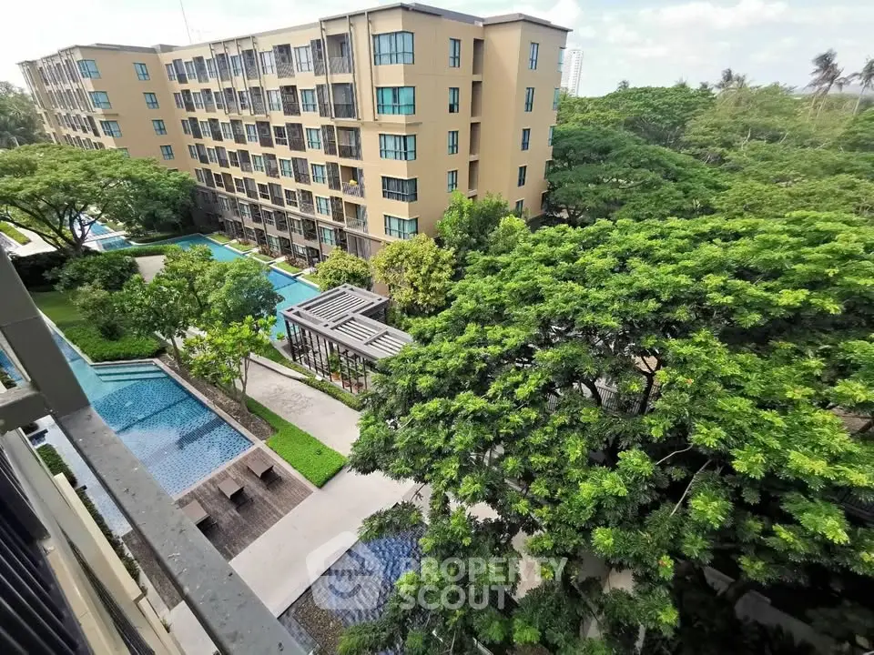 Stunning view of modern apartment complex with lush greenery and inviting pool area.