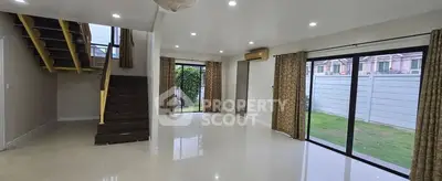 Spacious modern living room with large windows and staircase, perfect for family gatherings.