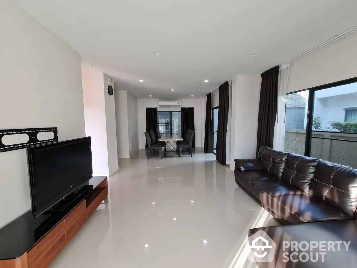 Spacious living room with glossy tiled floors, modern leather sofa, and a sleek dining area visible in the background, perfect for entertaining guests.