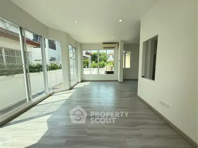 Spacious sunlit living room with large windows and modern flooring in a contemporary home.